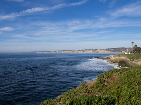 The La Jolla coast in San Diego: blue ocean below green bluffs and distant cliffs