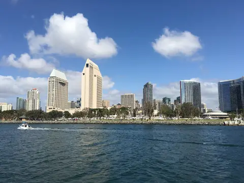 Downtown San Diego towers across the bay under a blue sky with white clouds