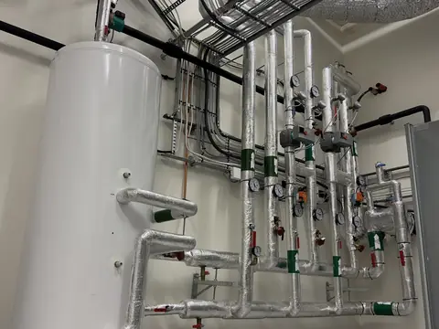 A tall water tank plumbed into a building's plant room