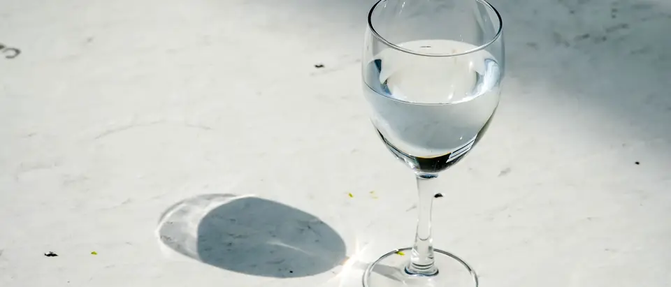 A glass of water on a sunlit marble counter