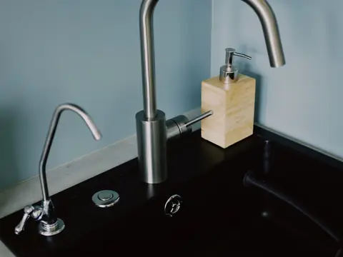 A kitchen sink with a stainless faucet and a small separate drinking water faucet
