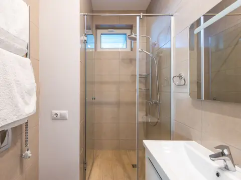 A bright bathroom with a glass shower enclosure, a towel rail and a white sink