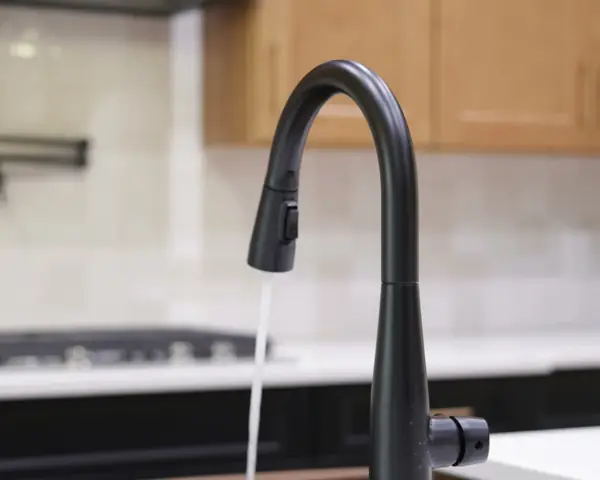 Clear water running from a matte black kitchen faucet in a bright kitchen