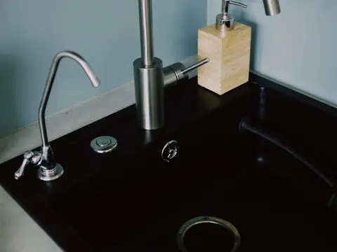 A kitchen sink with a stainless faucet and a small separate drinking water faucet