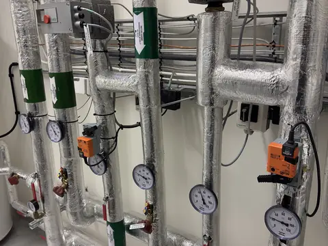 Insulated water lines with gauges and valves in a building's plant room