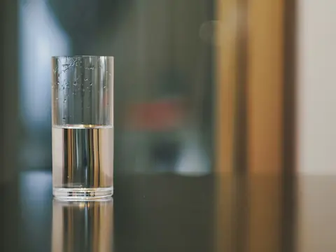 A glass half filled with water, catching reflections indoors
