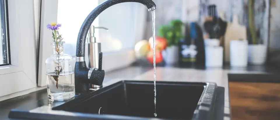 A modern kitchen sink with water running from a sleek faucet