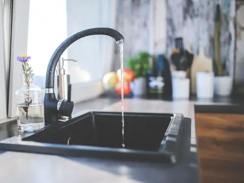 A modern kitchen sink with water running from a sleek faucet