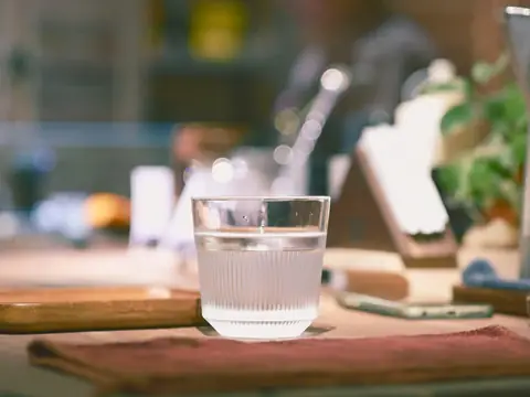 A glass of water on a wooden counter in a kitchen