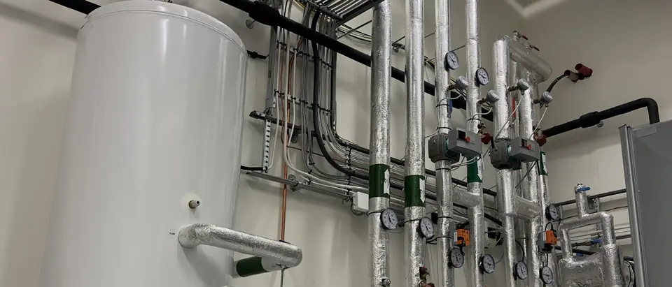 A tall water tank plumbed into a building's plant room