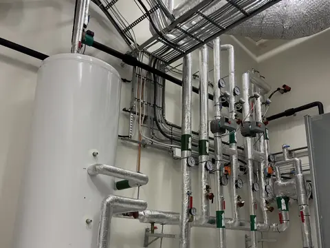 A tall water tank plumbed into a building's plant room